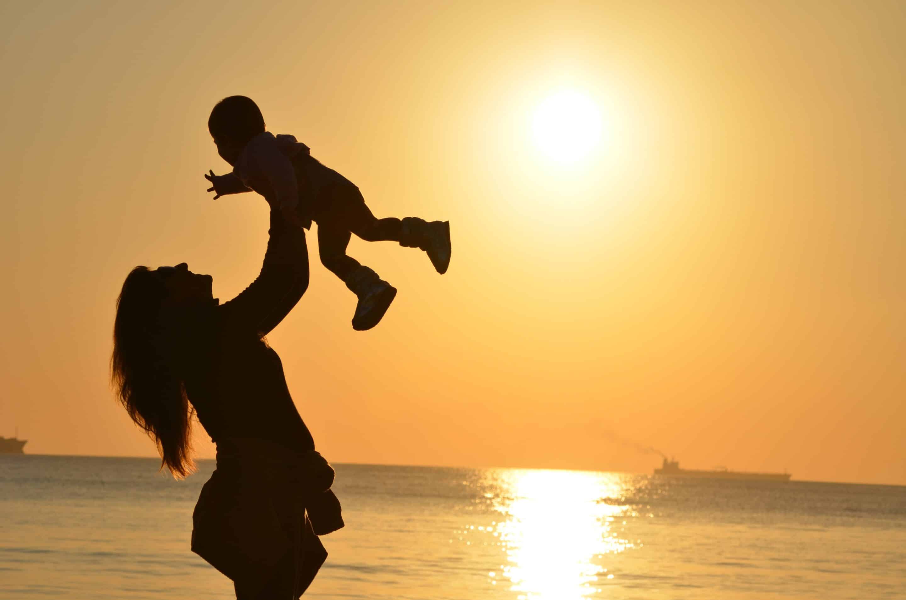 Mother holding child at sunset